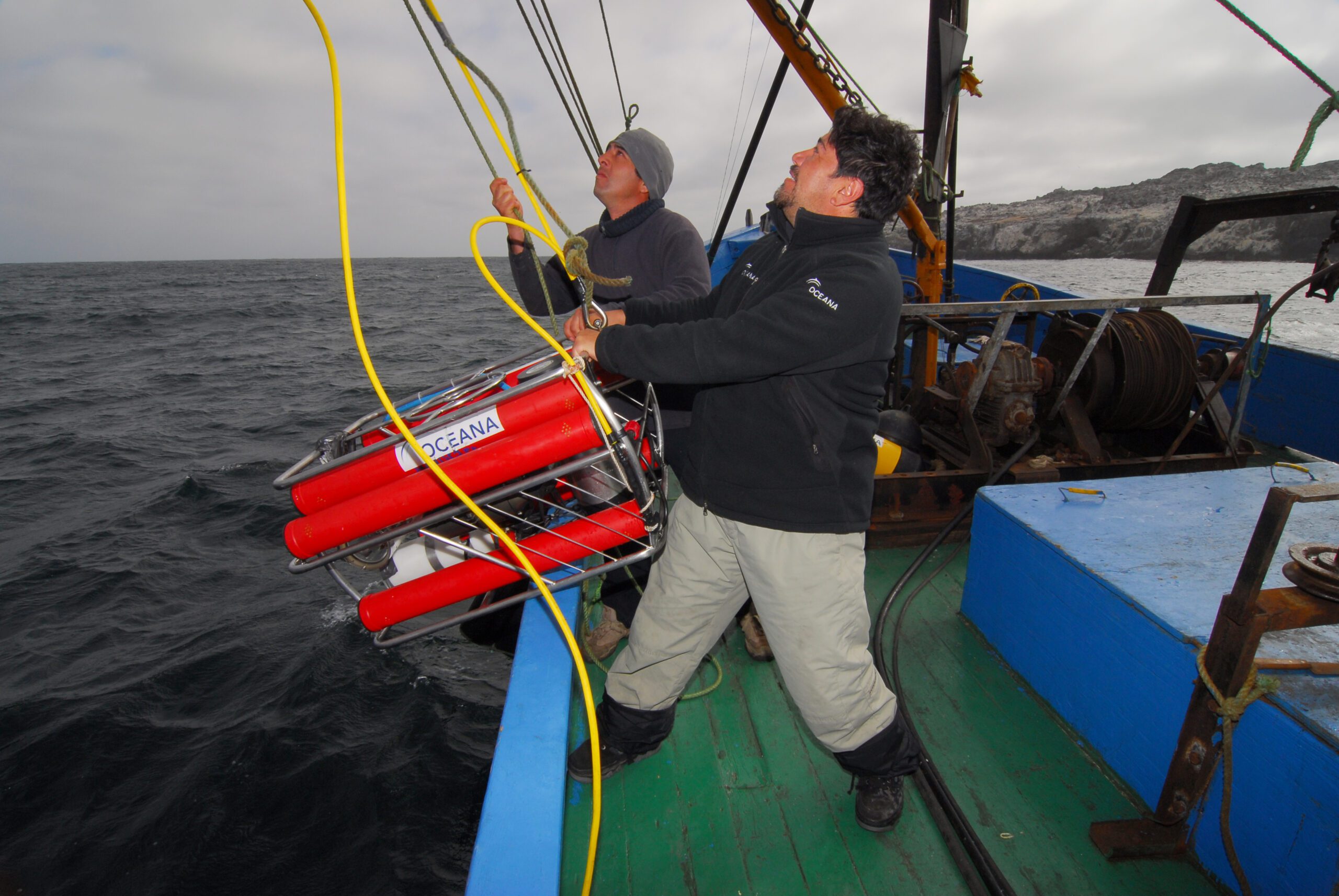 Two researchers lower a remotely operated vehicle into the Chilean ocean from a boat